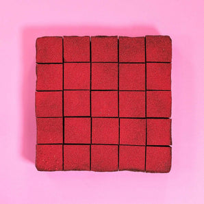 Raspberry & Dark Chocolate Brownie by Crumbs & Doilies, cut into squares with vibrant raspberry powder topping on pink background